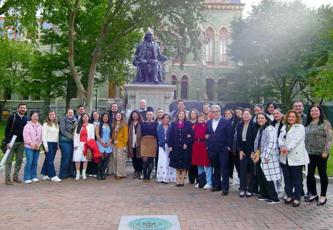 A large group of more than 30 academics from Penn GSE and University of Guadalajara pose for a group photo with the Ben Franklin statue on Penn’s campus.