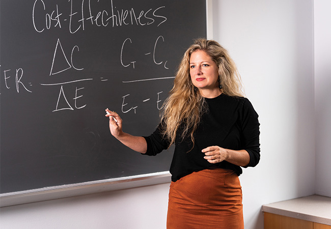 Brooks Bowden gesturing in front of a chalkboard with an equation.
