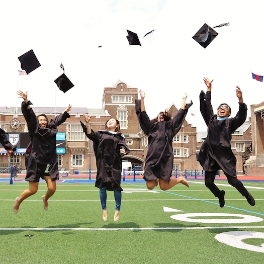 Four Penn GSE graduates jumping in the air as they throw their caps.