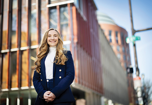 Lorea Peterson Rodondo stands in front of the Penn GSE building and Wharton's Huntsman Hall