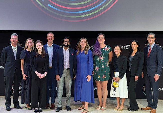 Unlocked Labs founder Jessica Hicklin (fourth from right), winner of the grand prize at the 14th annual Milken-Penn GSE Education Business Plan Competition, stands with others on stage at the competition finals