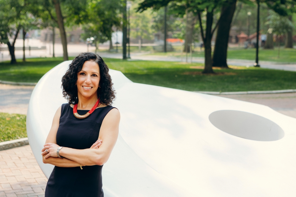 Dean Strunk smiling and standing with her arms crossed in front of the Split Button sculpture