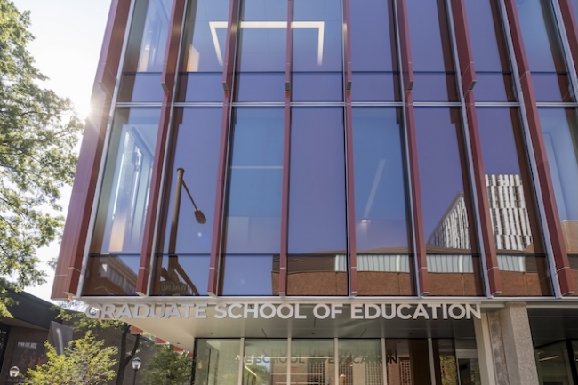 The sun flares on the front of the GSE building with the Graduate School of Education sign clearly visible