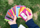 A set of colorful cards with words and images on them fanned out in a pair of hands.