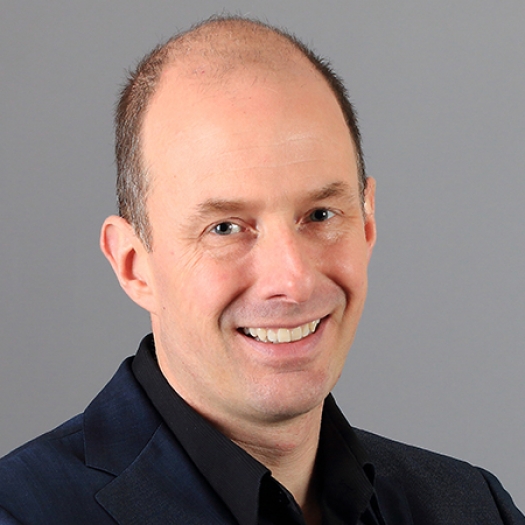 Headshot of a smiling man with a dark blazer