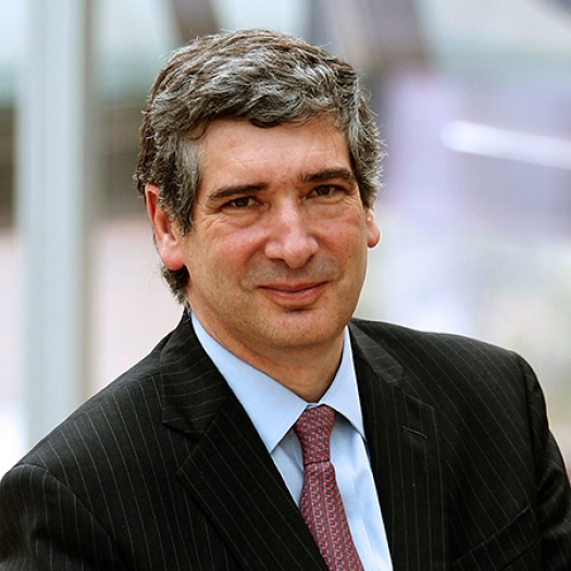Headshot of a man in a suit and tie sitting outdoors