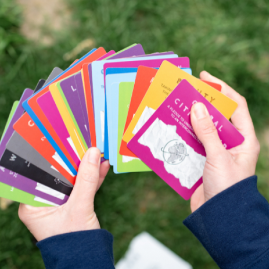 A set of colorful cards with words and images on them fanned out in a pair of hands.