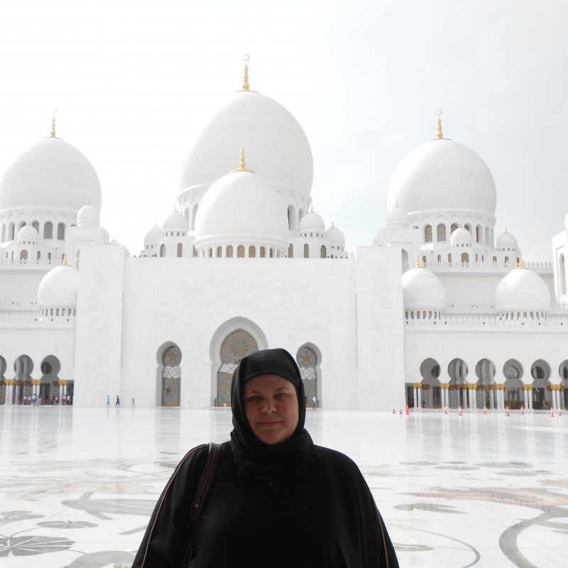 Young woman standing in front of grand, white building.
