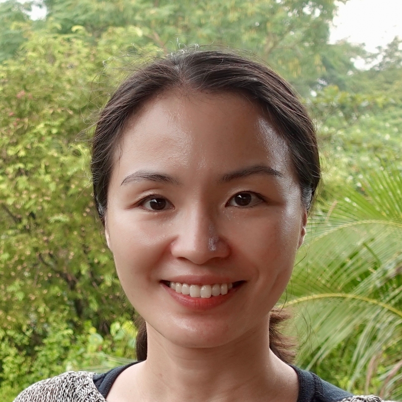 Headshot of Yangju Yi against tree backdrop