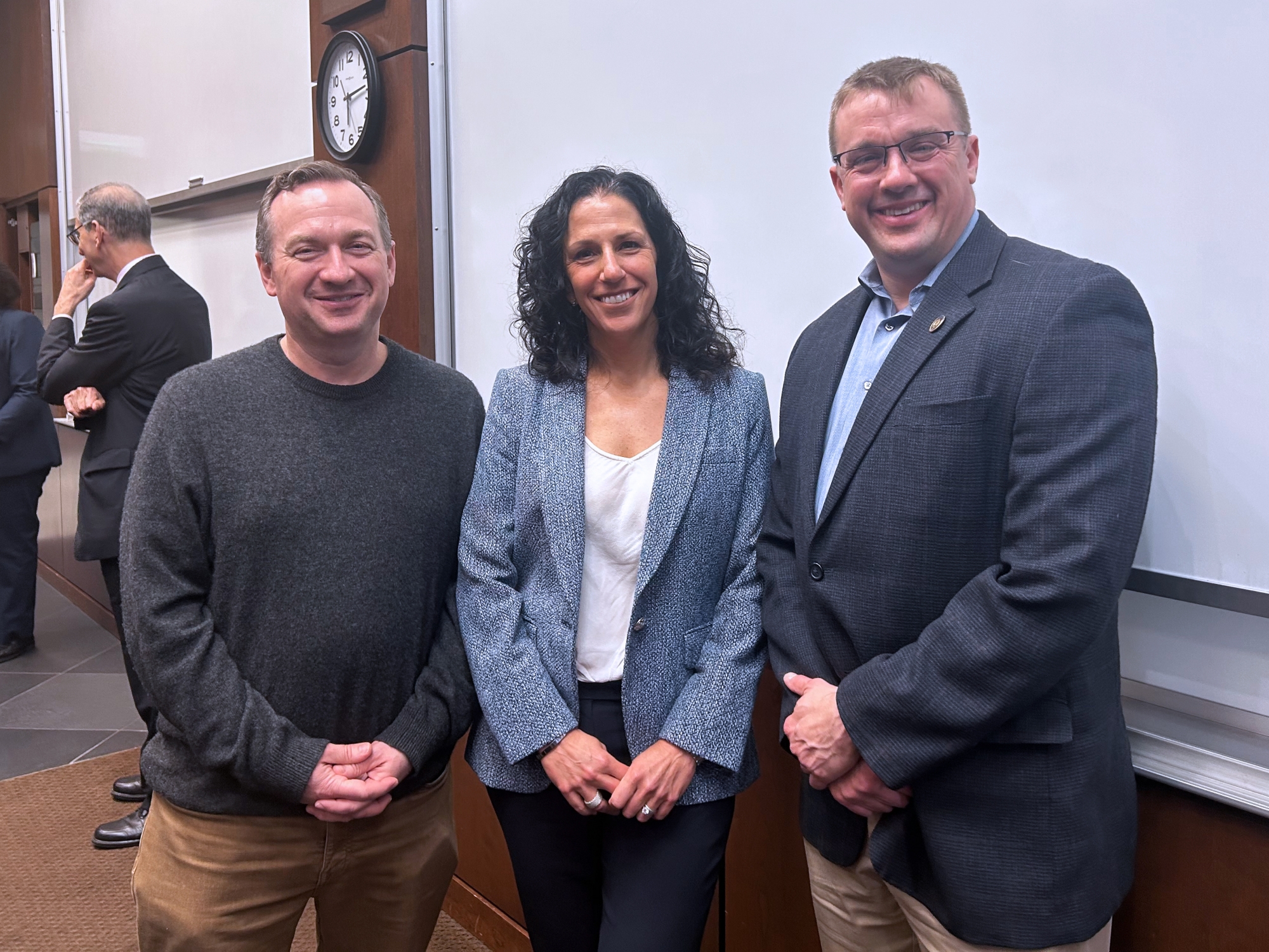 two legislators stand in a classroom with Dean Katharine Strunk