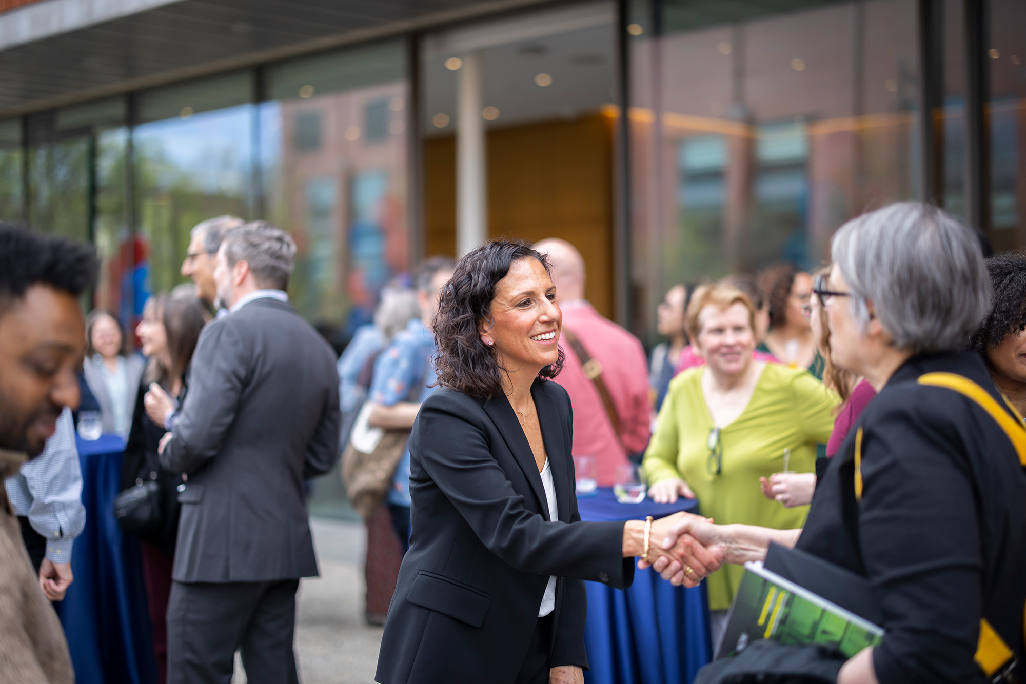 Penn GSE Dean Katharine Strunk greets attendees at an outdoor event.