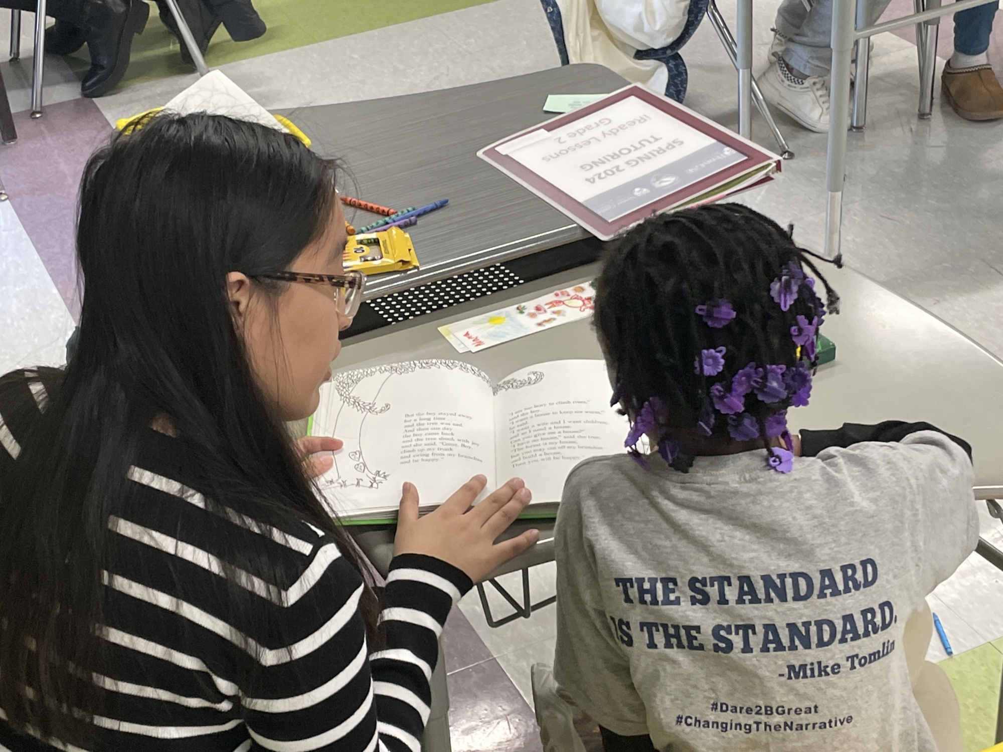 Penn Arts & Sciences undergrad Johana Muñoz tutors a Hamilton Elementary student in reading at a desk in a classroom