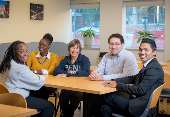 Dean Pam Grossman and students sitting indoors at a table